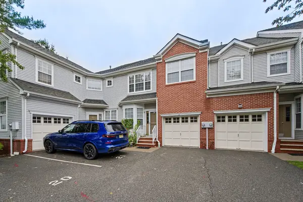 Front exterior with brick facade, attached garages and blacktop driveway