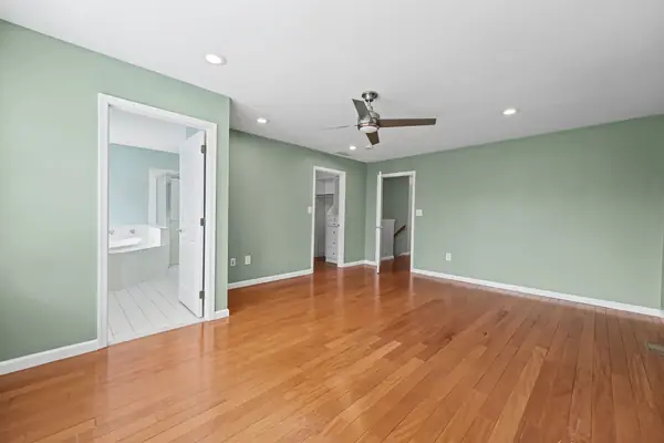Primary bedroom with hardwood floors, open to the en-suite bath